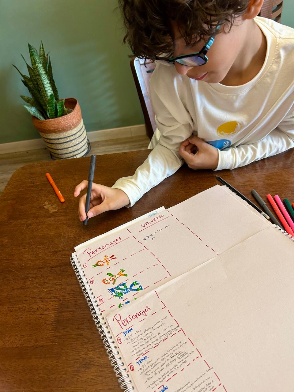 Niño escribiendo personajes en su cuaderno