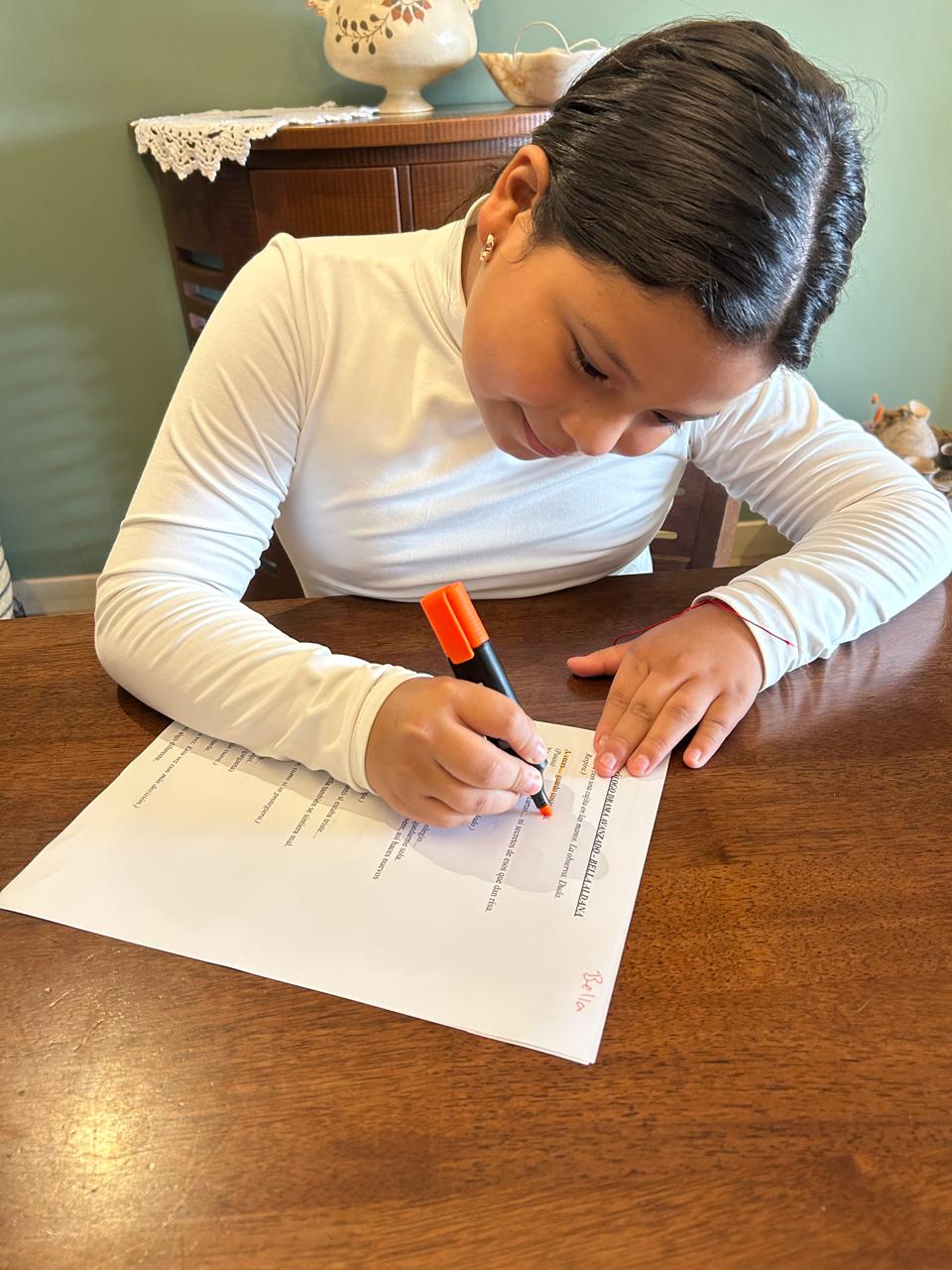 Niña escribiendo con marcador sobre su hoja creativa